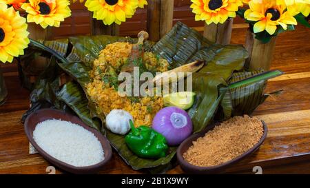 Tonga, cibo tipico della costa ecuadoriana, riso e carne cotti all'interno della foglia di palma, guarniti con un piatto di riso e arachidi, cipolla, aglio e Foto Stock