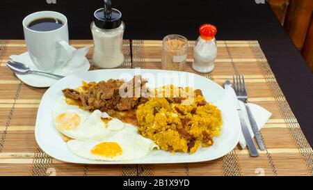 TIGRILLEO è un piatto tipico composto da banana verde macinato con formaggio servito in un piatto verde su un tavolo viola accompagnato da uova fritte e carne Foto Stock