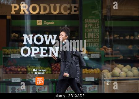 Una giovane donna cammina lungo Pike Street di fronte ad Amazon Go Grocery il 27 febbraio 2020. Il primo supermercato cashierless di dimensioni standard della società tecnologica è stato inaugurato nel quartiere Capitol Hill di Seattle all’inizio della settimana. I clienti eseguono la scansione di un'app Amazon Go per accedere al negozio di 10.000 piedi quadrati, prendere i prodotti e andare senza effettuare il check-out. La "Just Walk Out Technology" di Amazon utilizza un sistema complesso di telecamere e sensori per tenere traccia degli acquisti già in uso nei loro piccoli negozi Amazon Go. Foto Stock