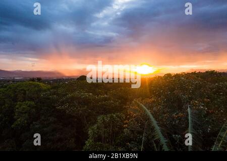 pioggia leggera che cade nella valle come il sole di impostazione aggiunge un bagliore colorato all'umidità nell'aria, foto presa da appena sopra la linea dell'albero e jus Foto Stock