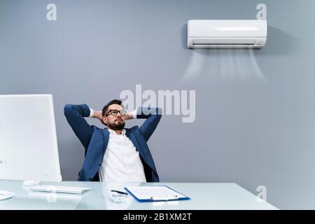 Un Uomo D'Affari Rilassato Che Si Gode Il Raffreddamento Dell'Aria Condizionata In Ufficio Foto Stock