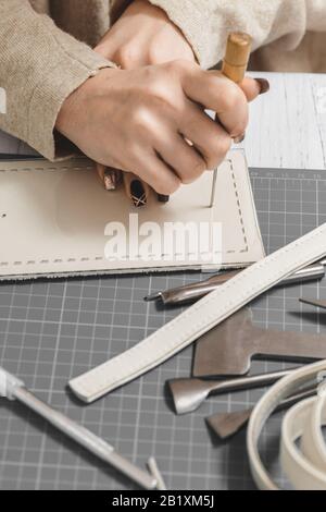 Primo piano delle mani di una donna che lavora con la pelle naturale. Master in borsa al lavoro in officina locale. Concetto di occupazione femminile Foto Stock