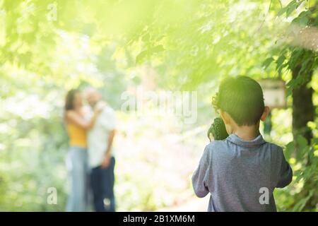 Ragazzino che fotografa i suoi genitori nei boschi. Foto Stock