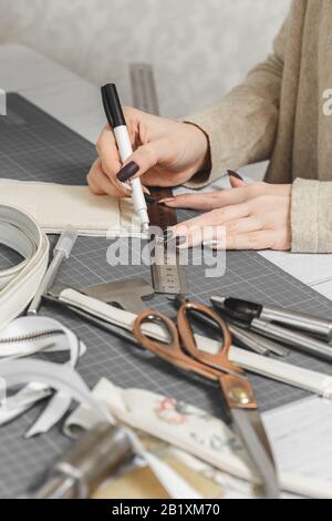 Borsa in pelle bianca per creare il processo. Mani di donna che lavorano in un workshop Foto Stock