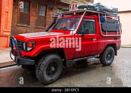 Primo piano della jeep sporca. In piedi su strada di pietra. Foto Stock