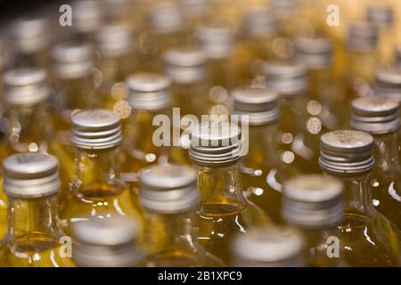 Primo piano / macro di bottiglie con un liquido giallo e un tappo a vite in alluminio. Può essere utilizzato come motivo o sfondo. Foto Stock