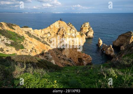 Lagos, Portogallo - 22 gennaio 2020: I turisti di Thrillseeker scattano foto con un telefono su una scogliera molto ripida nell'Algarve, di vedute panoramiche Foto Stock