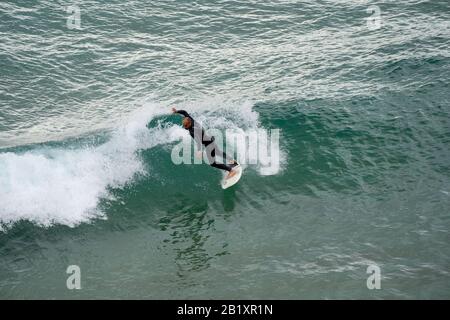 Sarges, Portogallo - 22 Gennaio 2020: Surfers catturano grandi onde sulla spiaggia di Praia do Beliche nella regione dell'Algarve in Portogallo Foto Stock