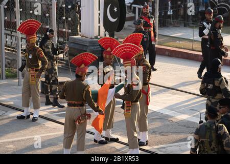 Attari, India - 8 febbraio 2020: La forza di sicurezza Di Frontiera indiana piega la bandiera dell'India dopo la cerimonia di chiusura di frontiera con il Pakistan Foto Stock