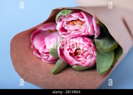 Un bouquet di tre tulipani in un involucro di carta si trova su un tavolo. Vista ravvicinata. Foto Stock