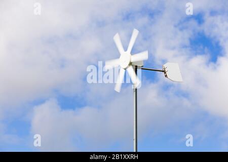 Piccola turbina eolica domestica contro un cielo blu, Inghilterra UK Foto Stock