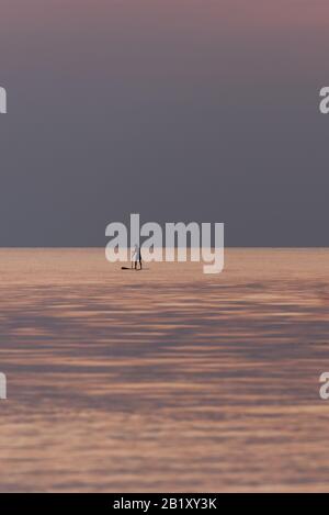 Stand up paddleboarding sul mare tranquillo Foto Stock