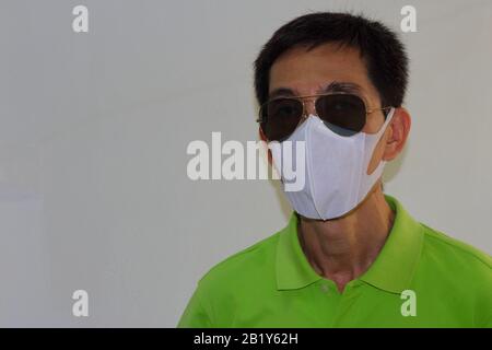 Faccia di primo piano di una persona che indossa occhiali da sole e maschera chirurgica per proteggere il covid 19 e cause di inquinamento atmosferico da PM2.5, concetto di sicurezza e cambiamento climatico Foto Stock