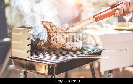 Chef maschile grill t-bone bistecca al barbecue cena all'aperto - uomo di carne di cucina per una famiglia barbecue pasto fuori nel giardino cortile - stile di vita Summe, cibo un Foto Stock