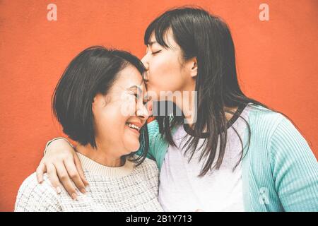 Figlia asiatica che bacia la mamma il giorno della madre - gente felice della famiglia che gode insieme del tempo - amore, stile di vita di maternità, concetto dei momenti tenaci - fuoco sopra Foto Stock