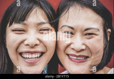 Ritratto di madre asiatica e figlia ridere di fronte alla macchina fotografica - Famiglia persone che hanno divertimento all'aperto - Maternità, felicità e teneri momenti concep Foto Stock