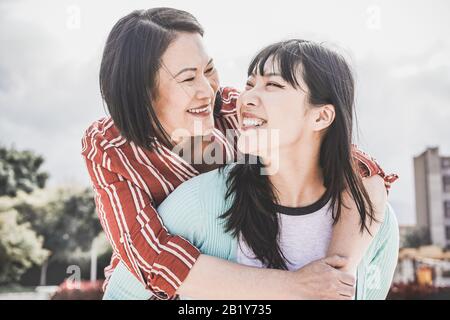 Madre asiatica e figlia che si divertono all'aperto - la gente felice della famiglia che gode il tempo insieme intorno alla città in Asia - amore, stile di vita di paternità, mamma tenera Foto Stock