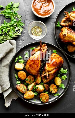 Gustose grigliate di quaglie carcasse sulla pietra nera dello sfondo. Quaglie arrosto sulla piastra. Vista superiore, laici piatta Foto Stock