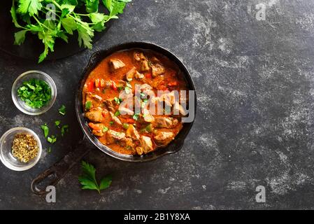 Peri-peri fegatini di pollo in padella su fondo di pietra nera con spazio di testo libero. Vista dall'alto, piatto Foto Stock