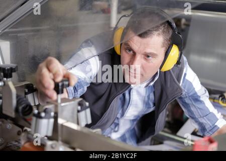 Ritratto di ingegnere maschio lavorando sulla macchina in fabbrica Foto Stock