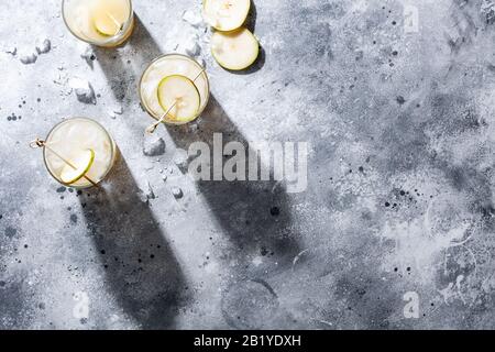 Un bicchiere corto di rinfrescante mocktail di acqua di soda di pera o un cocktail su sfondo grigio cemento. Bevanda estiva non alcolica. Orientamento orizzontale Foto Stock