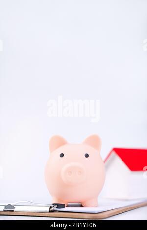 Banca piggy, modello di casa di legno bello sopra un contratto firmato su sfondo bianco, concetto di risparmio di soldi per comprare un'assicurazione domestica, primo piano, copia s. Foto Stock