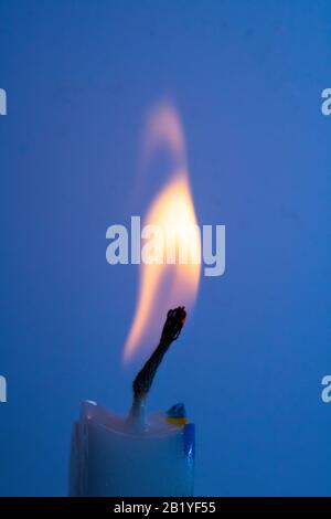 Un primo piano di una singola fiamma candela e un pulcino su sfondo colorato Foto Stock