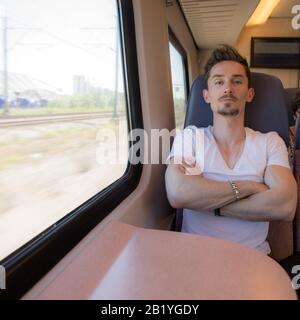 Giovane positivo bel uomo cavalcare un treno. Foto Stock