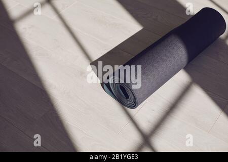 Tappeto yoga nero al piano di un luminoso studio soleggiato. Foto Stock