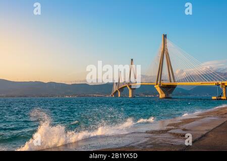 Grecia. Ponte Rion Antirion sul Golfo di Corinto. Spray di surf su argine di cemento. Luce del tramonto Foto Stock