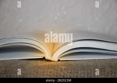 Libro aperto con fascio luminoso su sfondo tela Foto Stock