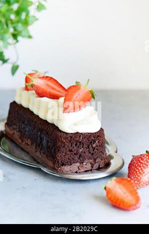 Brownie al cioccolato con crema alla vaniglia e fragole fresche. Torta al cioccolato con panna e frutti di bosco freschi. Tè dessert Foto Stock