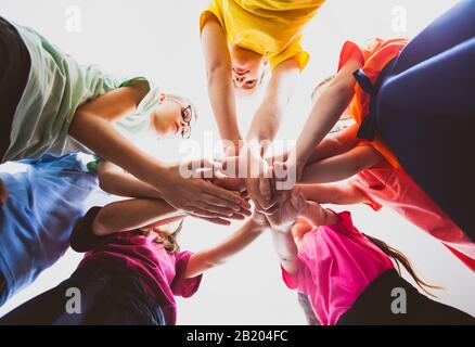 Molti bambini impilano le mani insieme. Simbolo del lavoro di squadra e della motivazione. Foto Stock