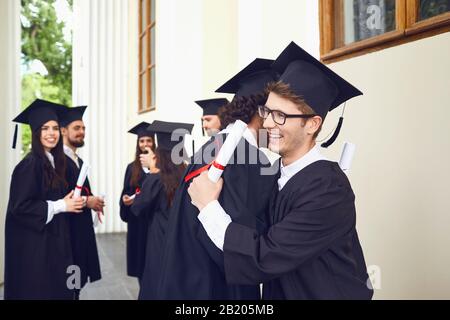 Donne laureati con diplomi nelle loro mani abbracciando Foto Stock