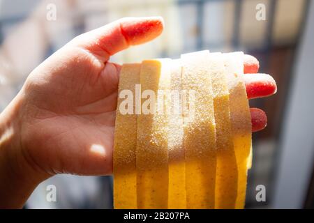 Mani femminili che tengono tagliatelle fatte in casa, pasta fresca tipica italiana Foto Stock