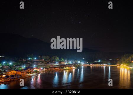 Paesaggio notte vista e Costellazioni di stelle di notte un piccolo villaggio nel mezzo delle montagne Con un grande fiume e la città in Ban Rak Th Foto Stock