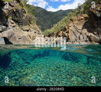 Fiume roccioso con acqua limpida, vista su e sotto la superficie dell'acqua, Oceania, Nuova Caledonia, Dumbea Foto Stock