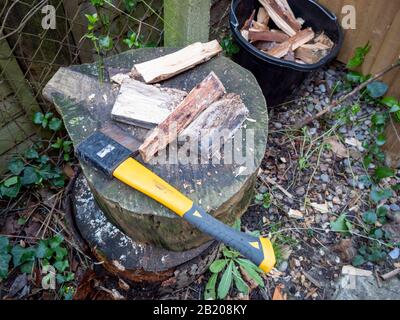 Un'ascia su un blocco di chopping con legno di accensione tritato pronto a bruciare sul fuoco domestico per il riscaldamento. Foto Stock