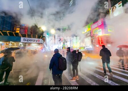 Il vapore che deriva circonda la gente, il traffico e gli edifici Di Times Square nella notte innevata al centro di Manhattan New York City NY USA il Gennaio 2020. Foto Stock