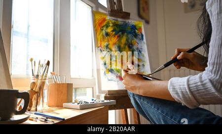 Artista di tiro corto donna mescolato colore e lavorare con pittura acrilica. Foto Stock