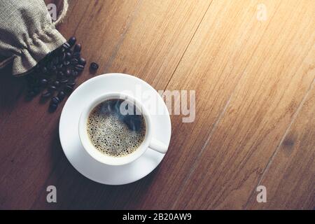 tazza di caffè bianco e chicchi di caffè su sfondo di legno. Vista dall'alto. Foto Stock
