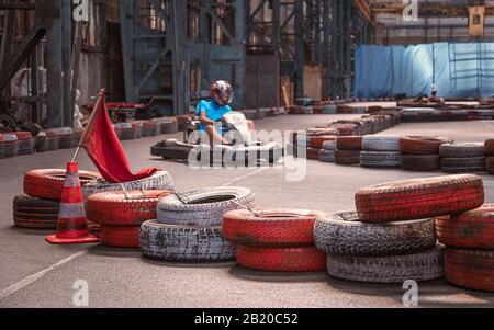 Ragazzo che guida un kart veloce su una pista interna Foto Stock