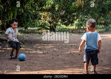 Fratelli ispanici che giocano a calcio/calcio sul campo della sporcizia nel villaggio guatemalteco Foto Stock