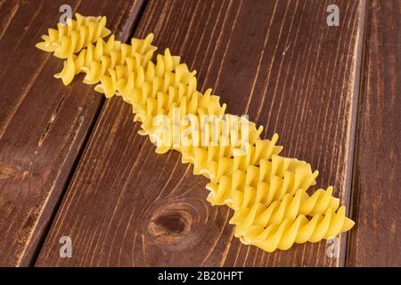 Lotto di pasta gialla intera fusilli su legno marrone Foto Stock