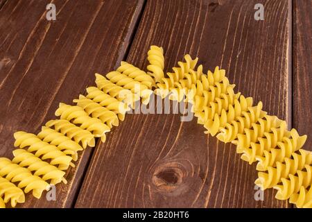Lotto di pasta gialla intera delta fusilli su legno marrone Foto Stock