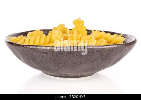 Lotto di pasta gialla intera fusilli in ciotola smaltata isolata su fondo bianco Foto Stock
