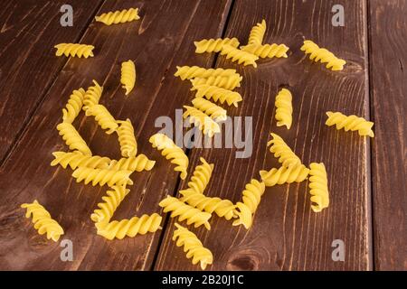 Lotto di pasta gialla intera fusilli su legno marrone Foto Stock
