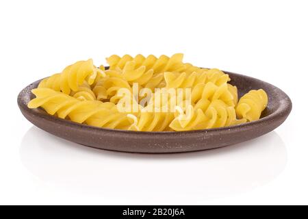 Molta pasta gialla intera fusilli con montagne russe di ceramica marrone isolate su sfondo bianco Foto Stock