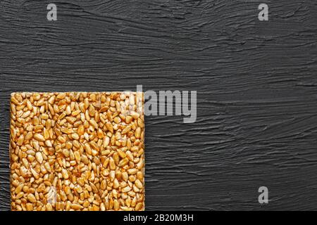 Spuntini utili. Alimentazione di dieta di idoneità. Boletchik da semi di girasole kozinaki, barrette energetiche. Sfondo textural nero Vista dall'alto. Spazio di copia, tasto basso Foto Stock