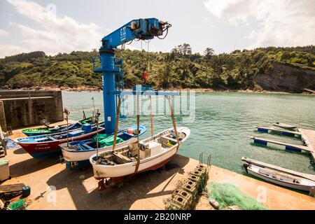 Tazones, Spagna. Una gru per barche a Tazones, una pittoresca città portuale sulla costa delle Asturie Foto Stock